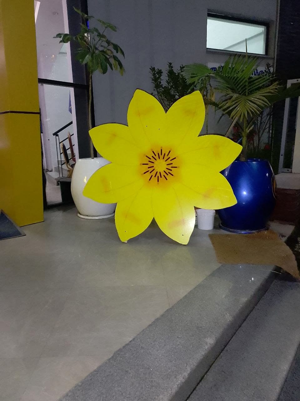 Large contour-cut yellow meskel flower prop standing in a lobby for the Fana 45th anniversary