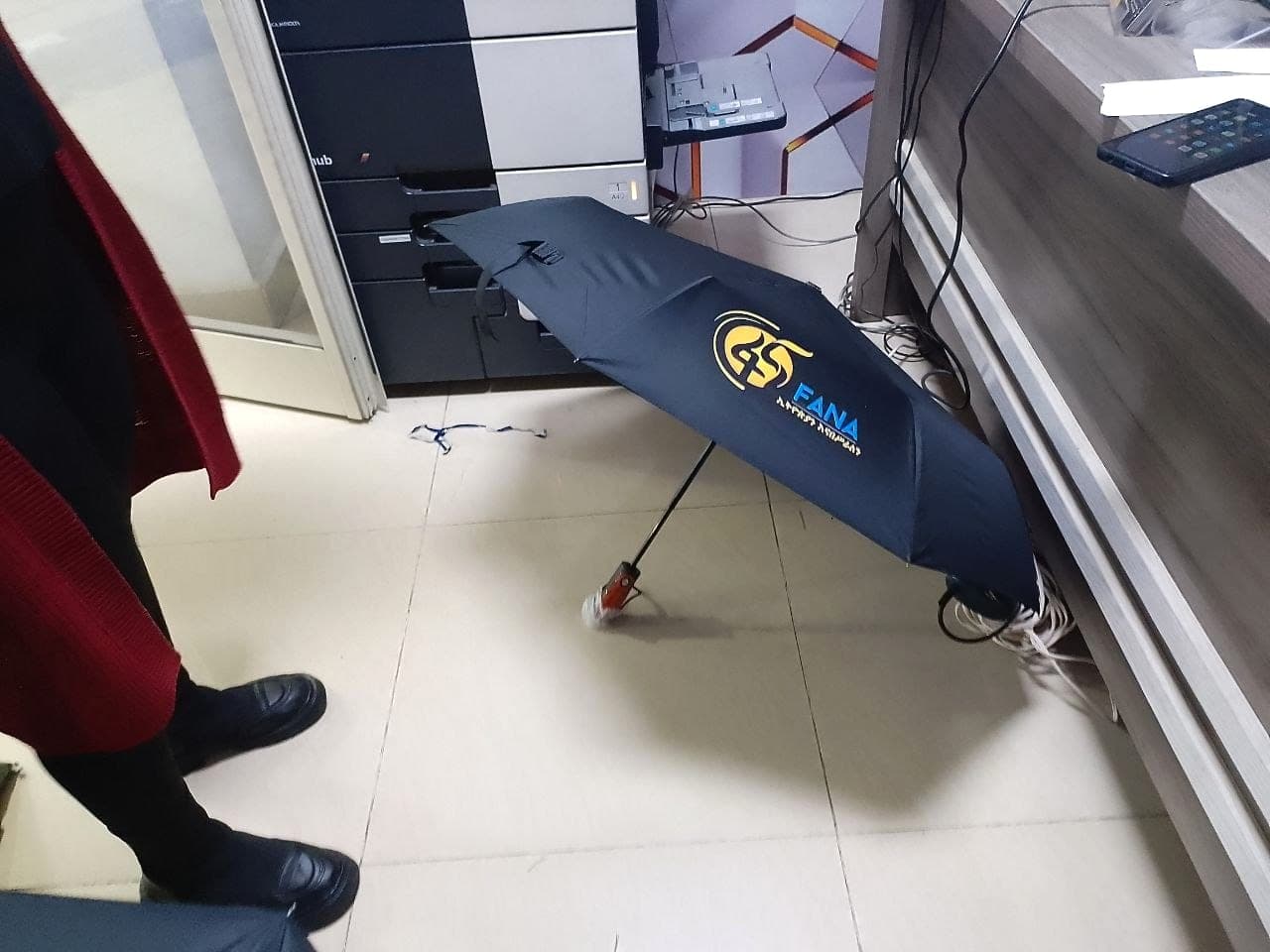 Single navy folding umbrella showing the gold Fana 45 logo and Amharic strapline printed across one panel