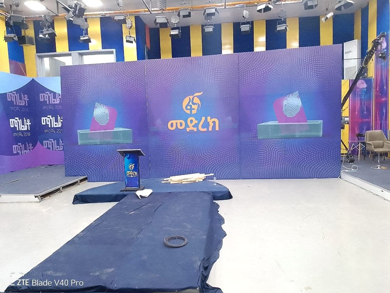 Television studio set built for Fana’s Medrek programme, with printed wall panels, plinths and a branded podium