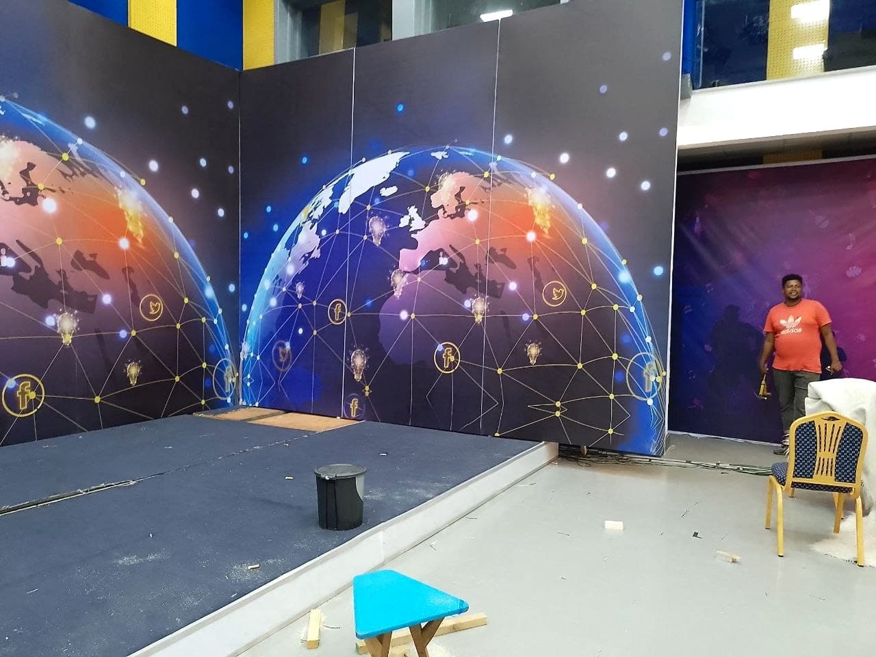 Large printed backdrop showing a connected globe being installed in an event hall