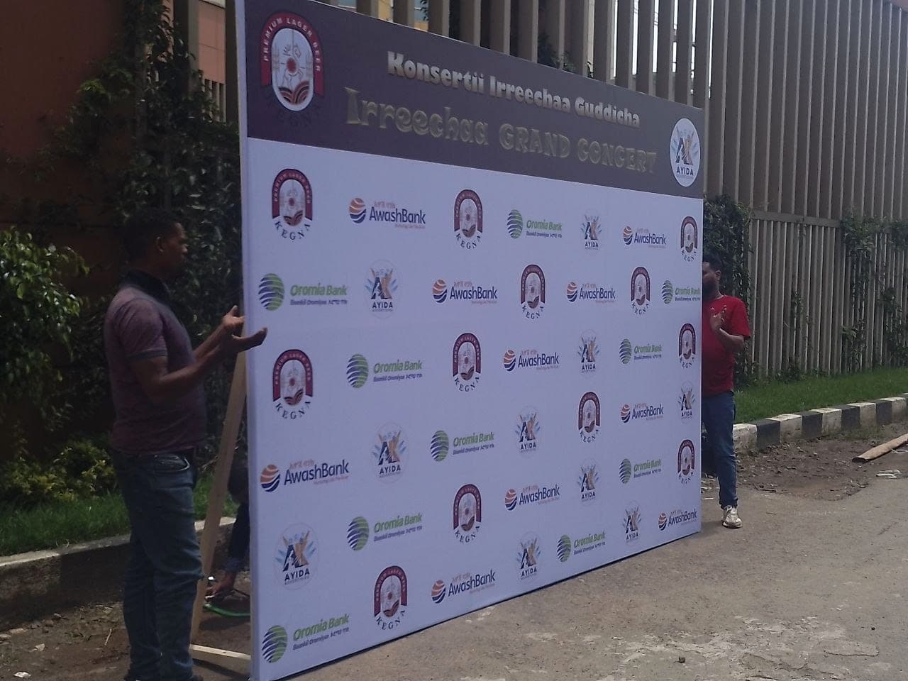 Two of the team lifting the Irreechaa Grand Concert sponsor wall into position on the street