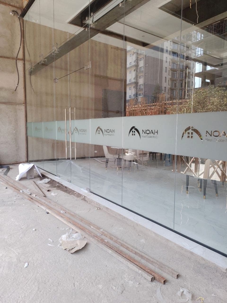 The finished frosted band of repeated Noah Real Estate logos running the length of a glazed office frontage
