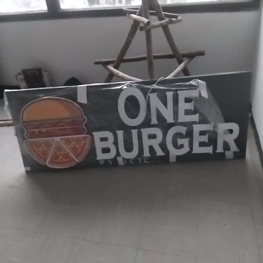 Finished One Burger shopfront sign panel, wrapped in protective film and standing ready to leave the workshop