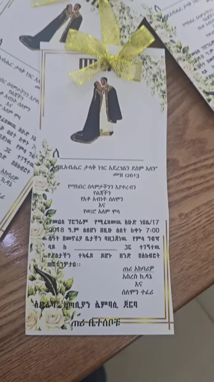 Wedding invitation cards with gold ribbon bows, spread across a table