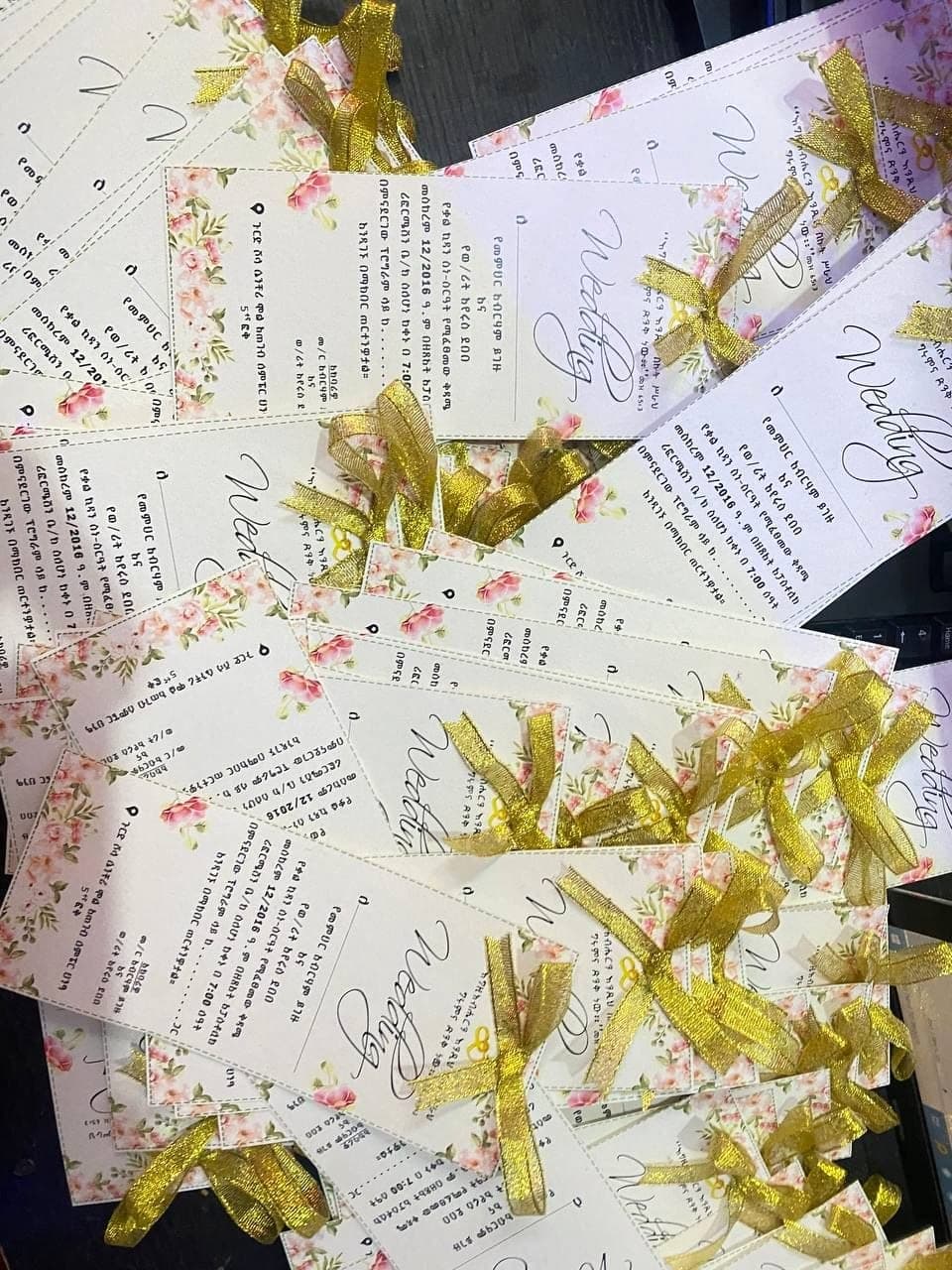 Floral wedding invitation cards tied with gold ribbon