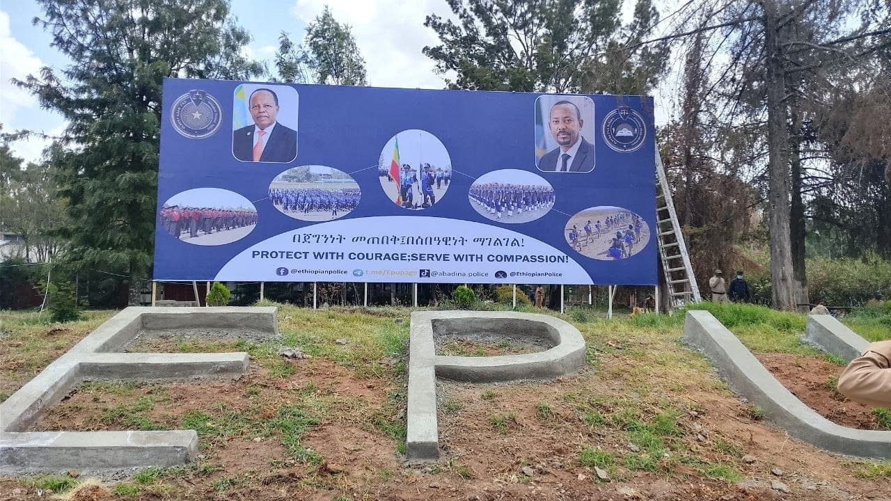 Large blue Ethiopian Police billboard reading "Protect with Courage; Serve with Compassion", with cast concrete letters standing in front of it
