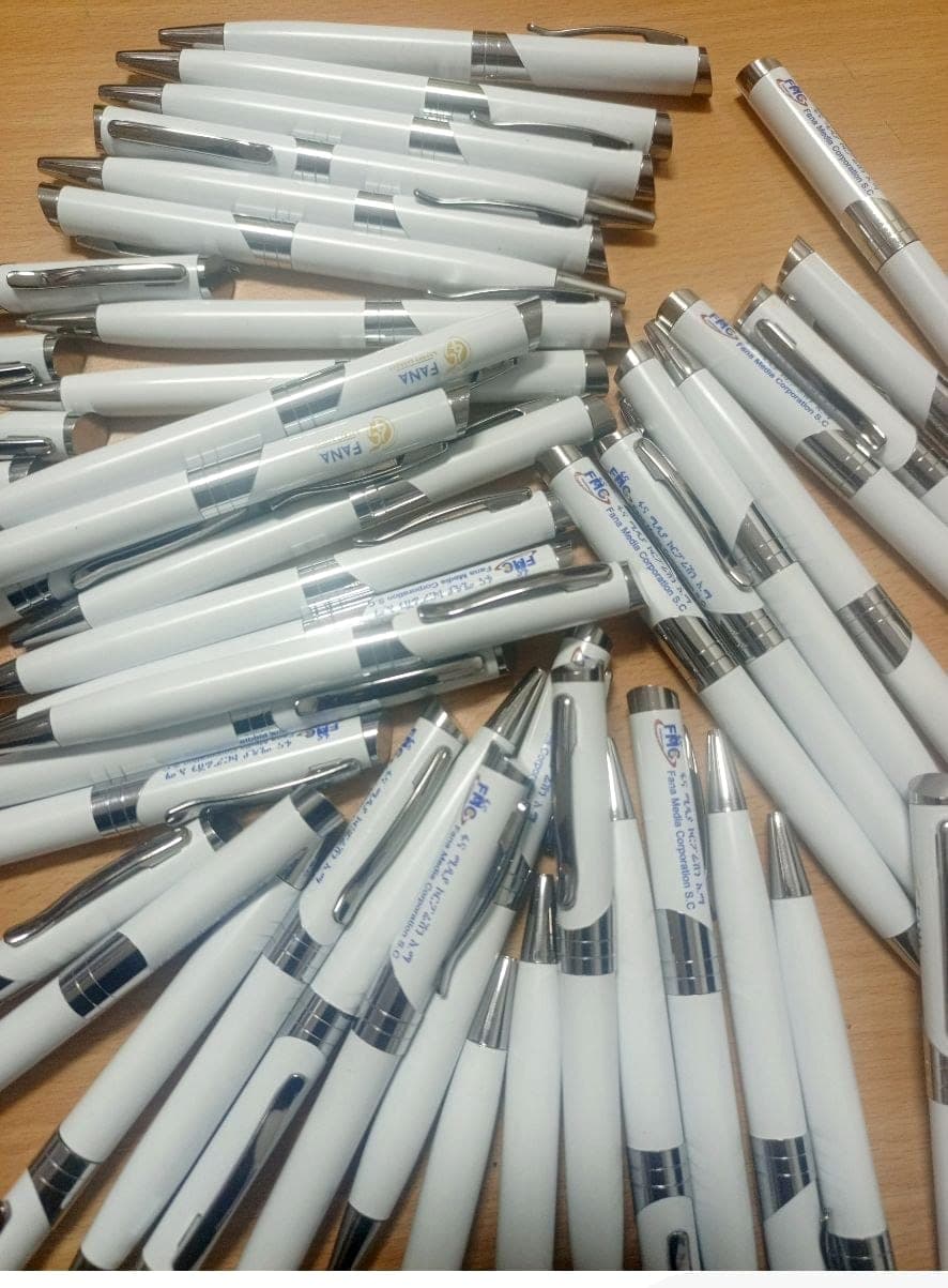 Pile of white and chrome pens printed with the Fana and Fana Media Corporation logos