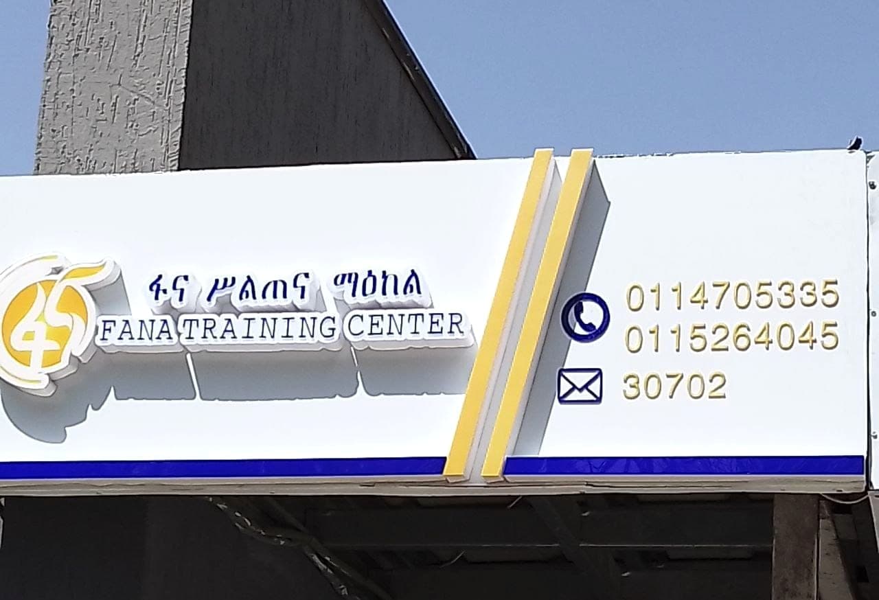 Raised white and blue fascia sign reading Fana Training Center above a shopfront